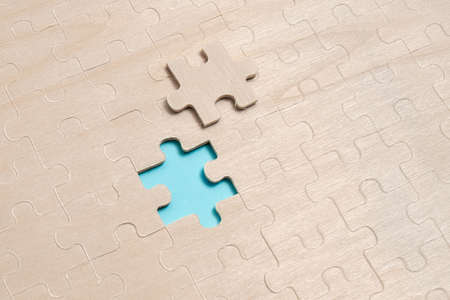 Close-Up White Jigsaw Pattern Puzzle Pieces To Be Connected With Missing Last Piece Positioned On A Flat Lay Background With Different Texture And Paper Supplies Accesoriesの写真素材