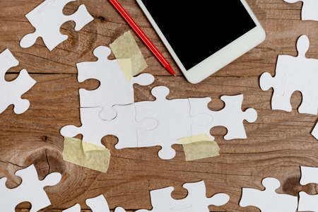 Close-Up White Jigsaw Pattern Puzzle Pieces To Be Connected With Missing Last Piece Positioned On A Flat Lay Background With Different Texture And Paper Supplies Accesoriesの写真素材