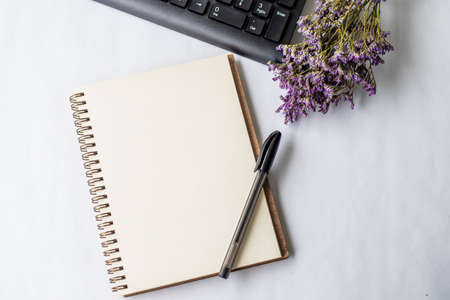 Empty Opened Journal With Pen Beside A Keyboard And A Flower On Top Of Desk, Blank Notepad With A Ballpen And A Floret Beside A Keypad Placed On A Table.の写真素材
