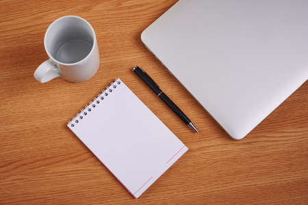 Closed Laptop Beside Empty Journal With Pen And Coffee Mug Over Table. Notebook Computer With Blank...