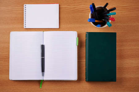 Plain Blank Open Notebooks With Stack Of Pens Inside Container Placed On Top Of A Table. Simple...