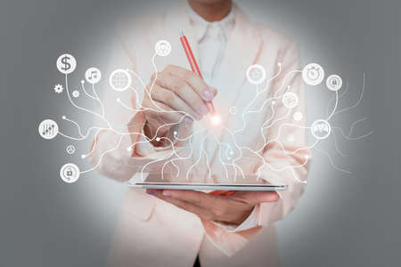 Lady In Uniform Standing Holding Tablet And A Pen Displaying Holographic Tech. Woman In Suit Carrying A Touchpad Showing New Futuristic Interface Technologies.の写真素材