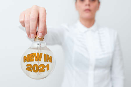 Text showing inspiration New In 2021. Conceptual photo what will be expecting or new creation for the year 2020 Lady in outfit holding lamp upside down presenting new technology ideasの写真素材