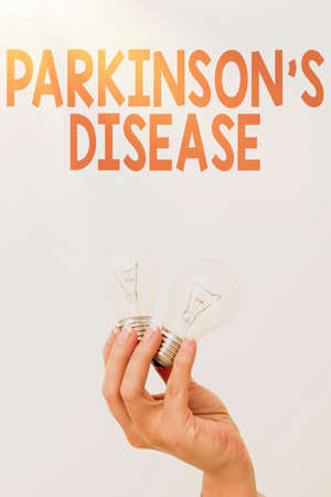 Text sign showing Parkinson S Is Disease. Business concept nervous system disorder that affects movement Hand holding two lamp showing or presenting new technology ideasの写真素材