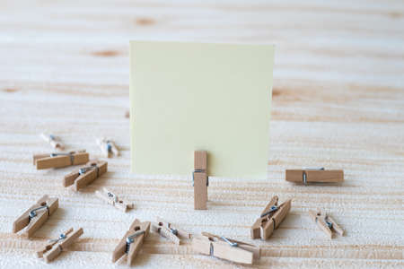 Blank Square Note Surrounded By Laundry Clips Showing New Meaning. Empty Piece Of Sticky Paper Clipped Upright Placed On Top Of Wooden Table Displaying Fresh Idea.の写真素材