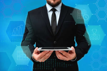 Man In Office Uniform Standing Holding Tablet Displaying New Modern Technology. Gentleman In Business Attire Carrying Tab Pointing New Futuristic Technology.の写真素材
