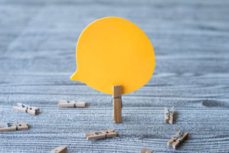 Piece Of Blank Speech Bubble Surrounded By Laundry Clips Showing New Meaning. Empty Conversation Balloon Clipped Upright Placed On Top Of Wooden Table Displaying Fresh Idea.の写真素材