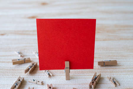 Piece Of Blank Square Note Surrounded By Laundry Clips Showing New Meaning. Empty Sticky Paper Clipped Upright Placed On Top Of Wooden Table Displaying Fresh Idea.の写真素材