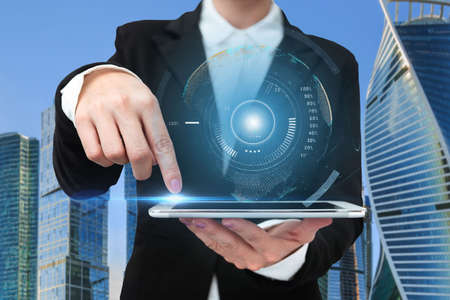 Woman In A Suit Pointing The Top Screen Of Tablet Showing Futuristic Technology. Businesswoman...