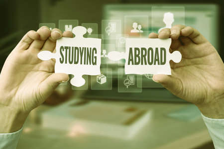 Handwriting text Studying Abroad. Concept meaning learn outside of home in foreign country Travelling Business Woman Holding Jigsaw Puzzle Piece Unlocking New Futuristic Tech.の写真素材