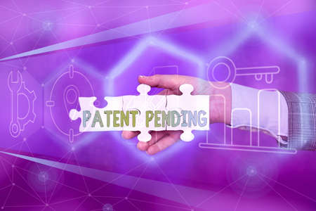 Sign displaying Patent Pending. Word Written on Request already filed but not yet granted Pursuing protection Hand Holding Jigsaw Puzzle Piece Unlocking New Futuristic Technologies.の写真素材