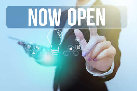 Hand writing sign Now Open. Business overview leave door or windows not closed or barred at this current time Woman In Uniform Carrying Phone And Tapping Futuristic Display.の写真素材