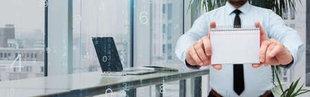 Businessman Holding Empty Page Graphing Notebook With His Both Hands Around Futuristic Technology....