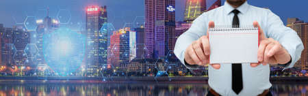 Businessman Holding Empty Page Graphing Notebook With His Both Hands Around Futuristic Technology. Employee Presenting Blank Workbook Surrounded By Modern Automation.の写真素材