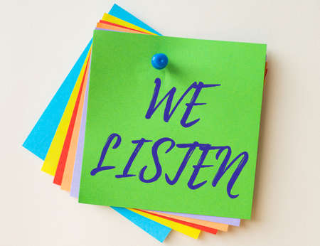 Writing displaying text We Listen. Conceptual photo Group of showing that is willing to hear anything you want to say Colorful Paper Notes Stacked Together And Pinned On The Wall.の写真素材