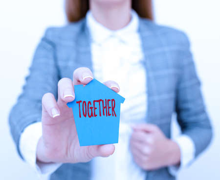 Writing displaying text Together. Business concept A close and harmonious relationship in which the showing or groups A Young Lady Businesswoman Holding Presenting Home In Business Outfitの写真素材