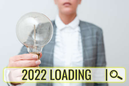 Conceptual caption 2022 Loading. Internet Concept Advertising the upcoming year Forecasting the future event Lady in business outfit holding lamp presenting new technology ideasの写真素材