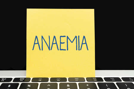 Conceptual caption Anaemia. Business concept a condition marked by a deficiency of hemoglobin in the blood Office Supplies Over Desk With Keyboard And Glasses And Coffee Cup For Workingの写真素材