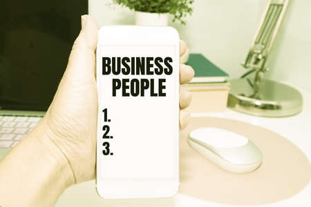 Hand writing sign Business People. Internet Concept People who work in business especially at an executive level Office Supplies Over Desk With Keyboard And Glasses And Coffee Cup For Workingの写真素材