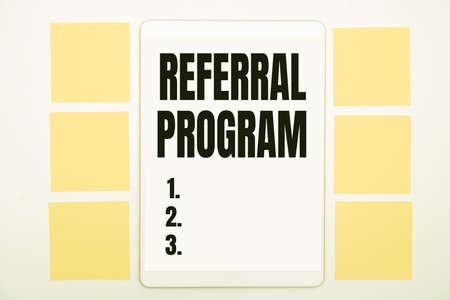 Hand writing sign Referral Program. Business idea sending own patient to another physician for treatment Office Supplies Over Desk With Keyboard And Glasses And Coffee Cup For Workingの写真素材