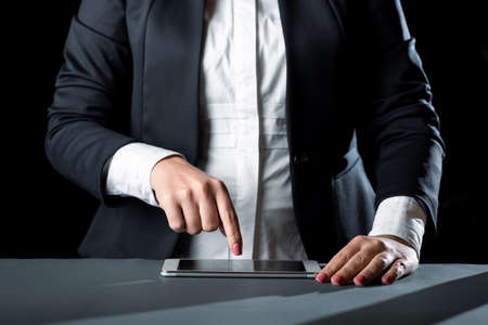 Businesswoman Having Tablet On Desk And Pointing On It With One Finger. Woman With Phone Showing...