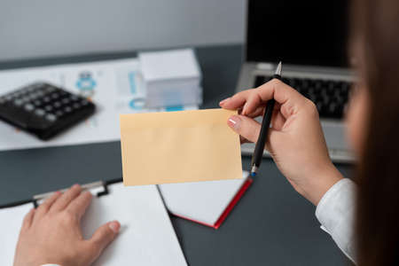 Businesswoman Holding Pen And Note With Important Message With One Hand. Woman Having Notebook With Crutial Information. Executive Showing Critical Data On Paper.の写真素材