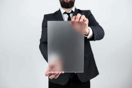 Male Professional Holding Blank Placard And Displaying Business Data. Businessman Wearing Suit Showing Rectangular Board For Marketing And Advertising The Company.の写真素材