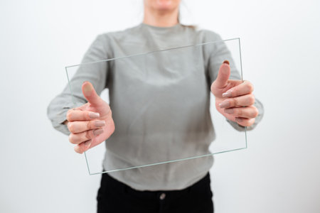 Female Professional Holding Transparent Glass And Displaying Important Data. Woman Wearing Smart Casual Showing Banner While Promoting The Business For Progress.の写真素材