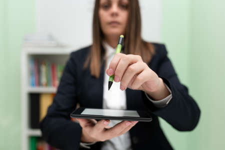 Businesswoman Holding Tablet And Pointing Important Informations With Pen In Hand. Woman Showing...
