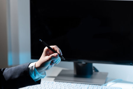 Businesswoman Holding Pen And Pointing On Important Messages On Table With Computer And Keyboard. Woman Presenting Crutial Information With One Hand.の写真素材
