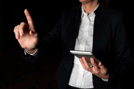 Businesswoman Holding Tablet And Pointing With One Finger On Important Message. Executive In Suit Presenting Crutial Information. Woman Showing Critical Announcement.の写真素材