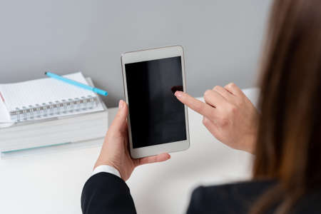 Businesswoman Holding Tablet And Pointing With One Finger On Important Message. Executive In Suit Presenting Crutial Information. Woman Showing Critical Announcement.の写真素材
