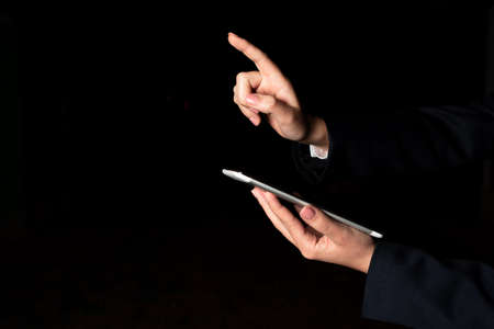 Businesswoman Holding Tablet And Pointing With One Finger On Important Message. Executive In Suit Presenting Crutial Information. Woman Showing Critical Announcement.の写真素材