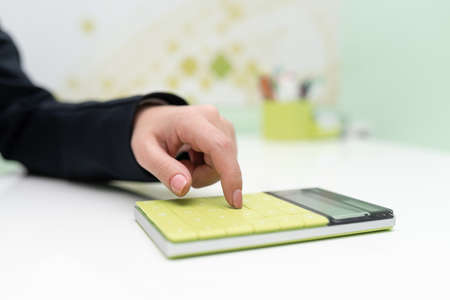 Businesswoman Pointing On Calculator On Desk With Notebook. Woman Pressing On Bottom On Table With...