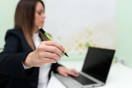 Businesswoman Typing Recent Updates On Lap Top Keyboard On Desk And Pointing Important Ideas With Pen. Woman In Office Writing Late Messages On Computer.の写真素材