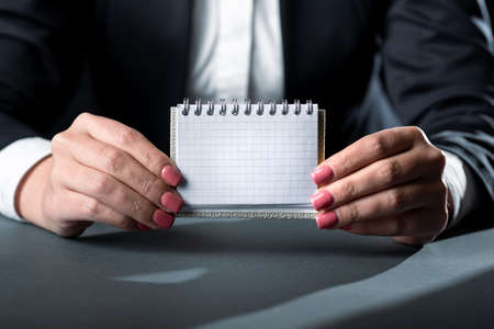 Businesswoman Holding Note With Important Message With Both Hands. Woman Having Small Notebook With...
