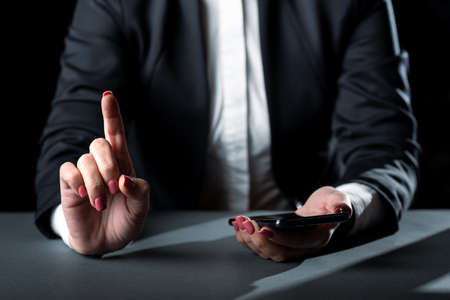 Businesswoman Holding Cellphone And Pointing Important Informations With One Finger. Woman Having...