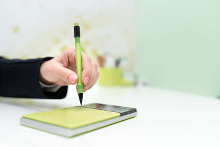 Businesswoman Pointing With Pen On Important Message With Calculator And Notebook On Desk. Woman Presenting News On Table With Notepad. Executive Displaying Recent News.の写真素材