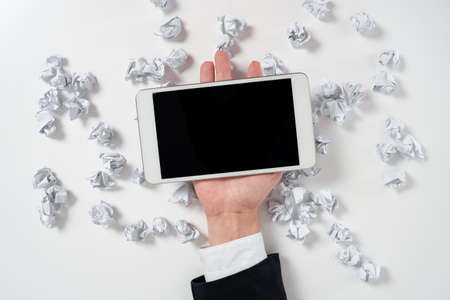 Paper Wraps Underneath Phone Screen With Important Message. Crumpled Notes Under Crutial Information On Tablet. Woman Presenting Recent Updates Above Wrinkled Notepaper.の写真素材
