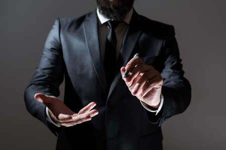 Businessman Holding Pen And Presenting Important Informations With One Hand And Showing Other Message Over Other. Man In Suit Showing Crutial Announcements With Pencil In Handの写真素材