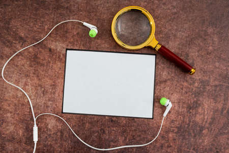 Blank Paper With Magnifying Glass And Headphones Placed On Wooden Table Presenting Research And...