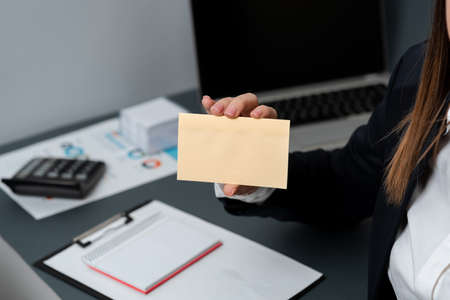 Businesswoman Holding Note With Important Message With One Hand. Woman Having Notebook With Crutial Information. Executive Showing Critical Data On Paperの写真素材