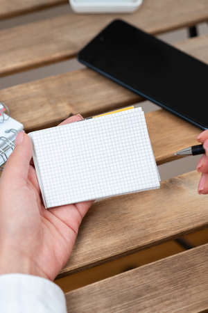 Businesswoman Holding Pen And Notepad With Important Message On Table With Phone. Woman Presenting...