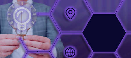 Businesswoman Holding A Light Bulb With Two Hands In A Graphic Hexagon Design. Woman Displaying Digital Information And Creative Ideas In A Presentation.の写真素材