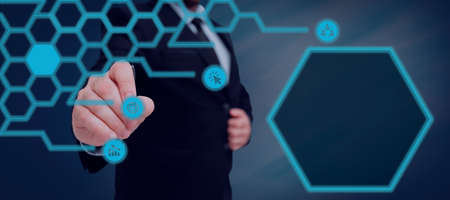 Businessman With A Pen And Pointing On Digital Symbols In A Glowing Hexagon Pattern. Man In A Suit...
