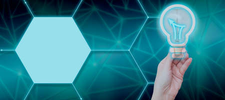 Businesswoman Hand Holding Illuminated Bulb With Graphical Light And Chart By Digital Hexagon Shapes. Woman Presenting Business Data And Sharing New Ideas For Development.の写真素材