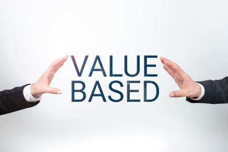 Writing displaying text Value Based. Business idea Considering the product worth in satisfying the customer Important Information Presented Between Business Team Hands.の写真素材