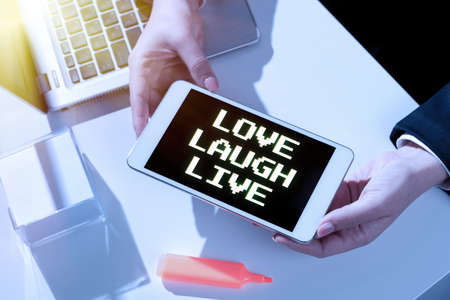 Text sign showing Love Laugh Live. Business overview Be inspired positive enjoy your days laughing good humor Businesswoman Presenting Important Message On Mobile Phone Screen On Desk.の写真素材