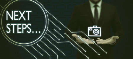 Sign displaying Next Steps . Word for numper of process going to be made after current one planning Businessman in suit holding open palm symbolizing successful teamwork.の写真素材