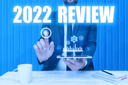 Sign displaying 2022 Review. Word Written on seeing important events or actions that made previous year Man holding Screen Of Mobile Phone Showing The Futuristic Technology.の写真素材